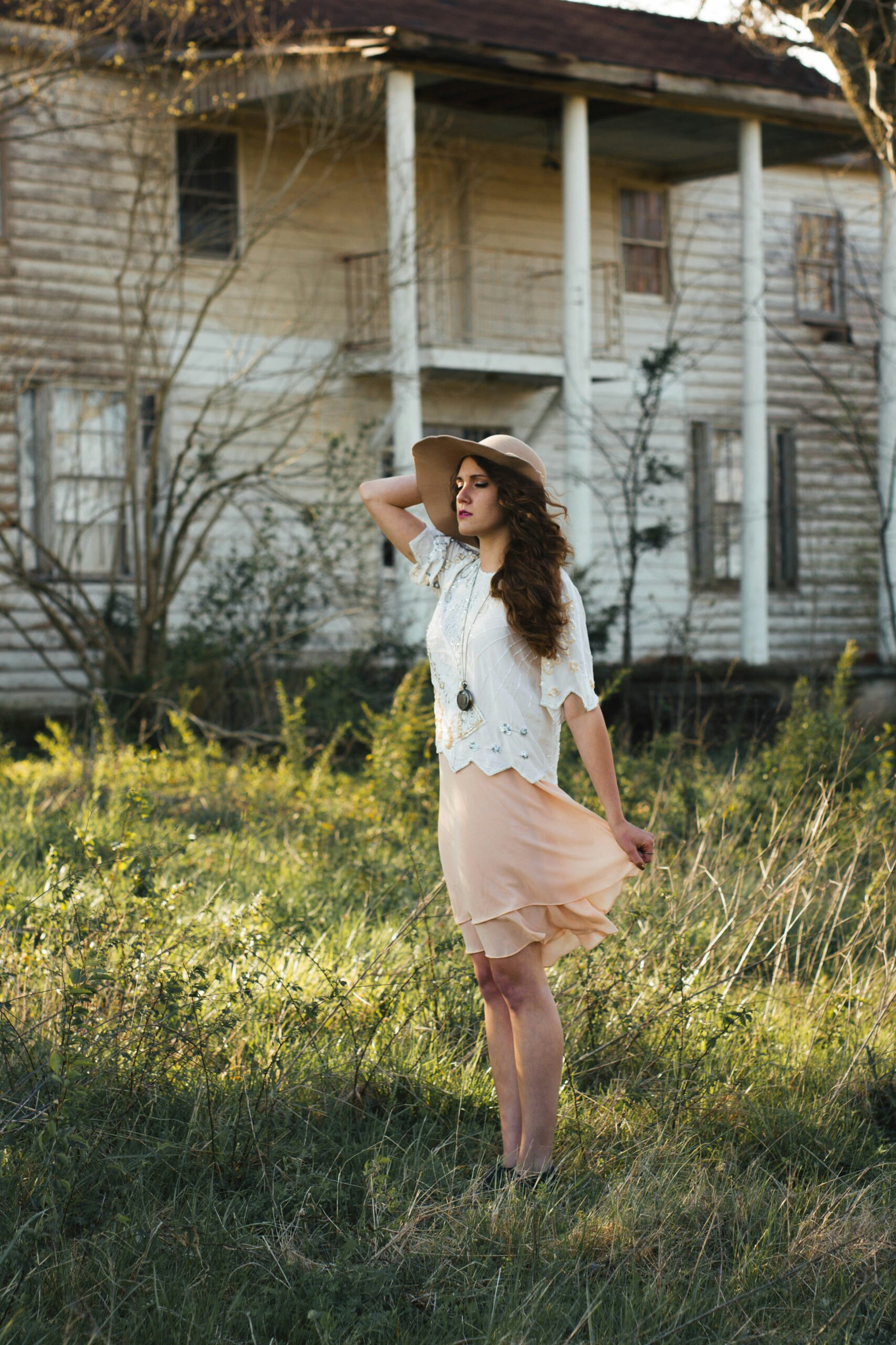 woman wearing brown sun hat standing on grass near white house